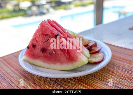 Colpo di primo piano di anguria a fette e prugne in plastica piastra Foto Stock