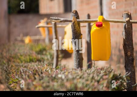 Galloni di acqua riciclati e adattati su tronchi di albero come stazioni di lavaggio delle mani per i bambini per lavare le loro mani sulle porte della classe. Noto anche come tippy tap Foto Stock