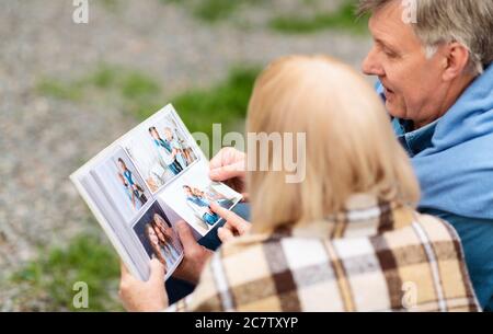 Condividere ricordi felici. Uomo anziano con sua moglie che sfogliava l'album fotografico all'aperto Foto Stock