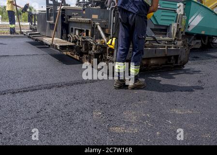 Asfaltatrice in funzione durante la costruzione di strade Foto Stock