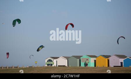 Kite Surfers in azione nel mare al largo di Lancing spiaggia con una vista sulle capanne spiaggia Foto Stock