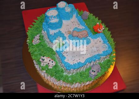 Torta di compleanno rotonda verde per bambini con pois di polka rossi, gialli, blu e rosa e carino bambino fondente blu sulla parte superiore. Foto Stock