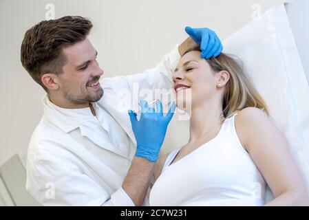 Primo piano di un medico che esegue la chirurgia estetica su un giovane femmina sotto le luci Foto Stock