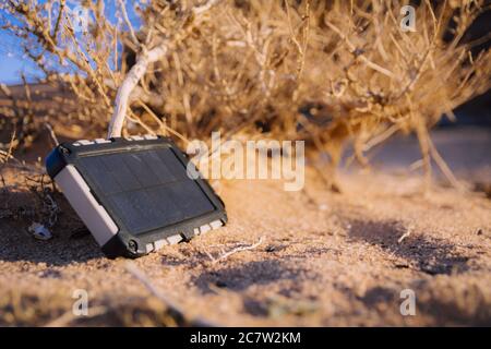 Robusto power bank con pannello solare che carica l'elettricità in natura e sabbia del deserto Foto Stock