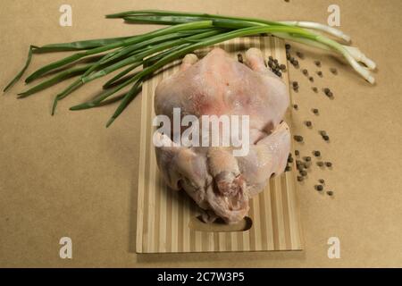 Carcassa di pollo cruda, pollo. Carcassa di pollo cruda con spezie ed erbe su un tagliere su un tavolo di legno Foto Stock