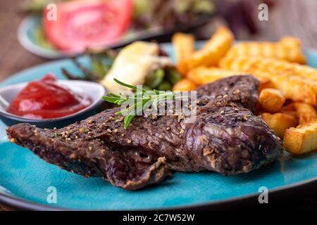 rosmarino su una bistecca con patatine fritte Foto Stock