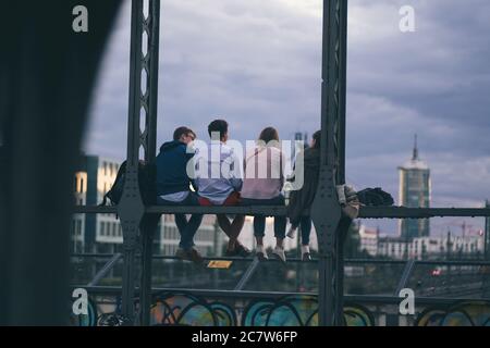 MONACO, GERMANIA - 30 giugno 2020: Gli amici trascorrono una serata rilassante su un ponte con vista sulla città. Luogo di incontro serale per giovani e studenti in M Foto Stock