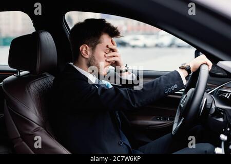 Uomo d'affari triste che guida da solo nella sua nuova auto Foto Stock