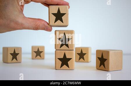 Mano maschile posizionare un cubo con l'icona a stella sopra un altro cubo. Immagine concettuale di qualità e lusso. Splendido sfondo bianco. Spazio di copia. Foto Stock