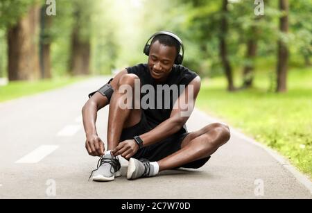 Sportivo africano ragazzo legando le sue scarpe sportive prima di fare jogging mattina Foto Stock