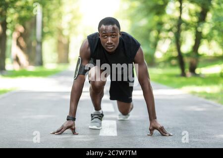 Uomo nero jogger in posizione pronta, allenarsi al parco Foto Stock