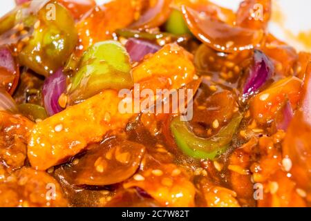 Patate al peperoncino al miele in salsa piccante, semi di sesamo e cipolle verdi da vicino, cibo popolare indiano-cinese. Fuoco selettivo Foto Stock