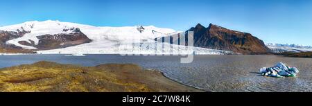 Vista panoramica degli iceberg che si fondono galleggianti nel lago glaciale di Fjallsarlon con il ghiacciaio di Fjallsjokull che calpita in laguna sullo sfondo. Luogo: FJA Foto Stock