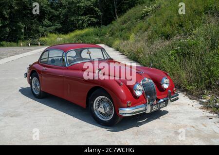 Red Nineteen Fifties Jaguar XK150 coupé parcheggiato su una corsia di campagna nello Yorkshire in una soleggiata giornata estiva Foto Stock