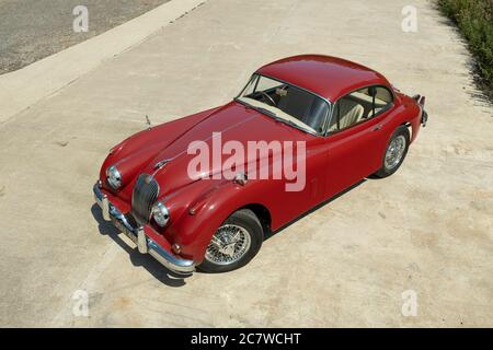 Red Nineteen Fifties Jaguar XK150 coupé parcheggiato su una corsia di campagna nello Yorkshire in una soleggiata giornata estiva Foto Stock