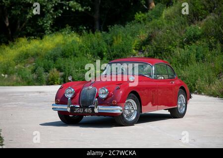 Red Nineteen Fifties Jaguar XK150 coupé parcheggiato su una corsia di campagna nello Yorkshire in una soleggiata giornata estiva Foto Stock