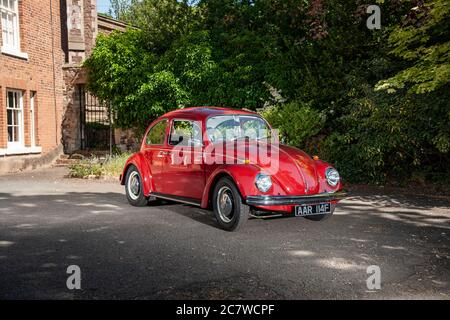 Volkswagen Beetle parcheggiato sul cortile di una casa in un pomeriggio estivo soleggiato Foto Stock