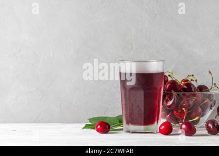 Succo di ciliegia in un bicchiere con frutti di bosco freschi su sfondo bianco. Rinfresco estivo drink. Bevanda sana Foto Stock