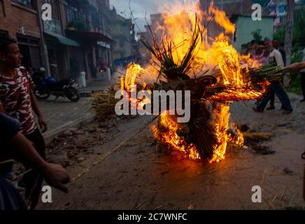 Un devoto nepalese trascina l'effigie bruciante di Ghantakarna durante le celebrazioni.Ghantakarna festival è una celebrazione nella sconfitta del mitico demone Ghantakarna, inseguire gli spiriti malvagi e portare buone fortune. Foto Stock