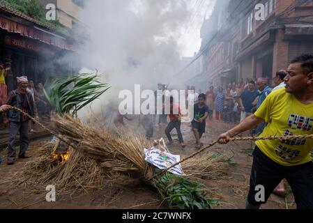 Un devoto nepalese che tira l'effigie bruciante del demone Ghantakarna durante le celebrazioni.Ghantakarna festival è una celebrazione nella sconfitta del mitico demone Ghantakarna, inseguire gli spiriti malvagi e portare buone fortune. Foto Stock