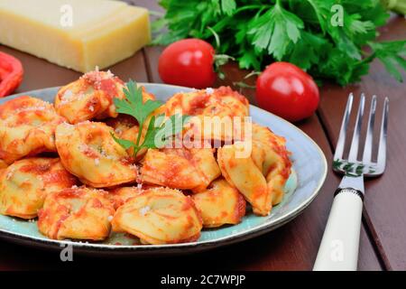Tortellini tradizionali italiani in un piatto su un tavolo di legno marrone Foto Stock