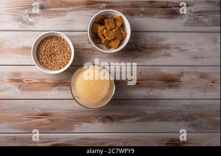 Vista dall'alto in casa tradizionale russo segale leggero kvass in vetro e cracker su sfondo di legno. Ottima bevanda rinfrescante per l'estate Foto Stock