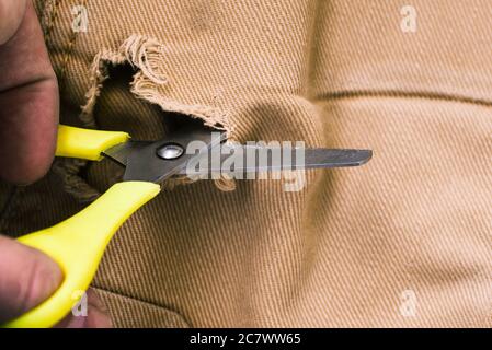 Le forbici tagliano il denim. Vecchi jeans. Riparazione e cucitura dei vestiti. Foto Stock