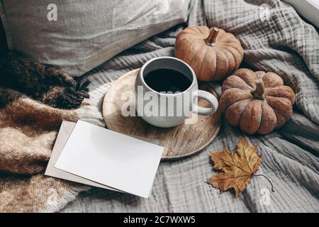 Composizione autunnale dallo stile femminile. Colazione autunno ancora vita. Oscura scena di mock-up di biglietto d'auguri con tazza di caffè, coperta di lana, foglia d'acero e. Foto Stock