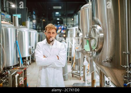 Ritratto di esperto professionale di tecnologo caucasico in uniforme bianca in fabbrica farmaceutica o alimentare - stabilimento di produzione Foto Stock