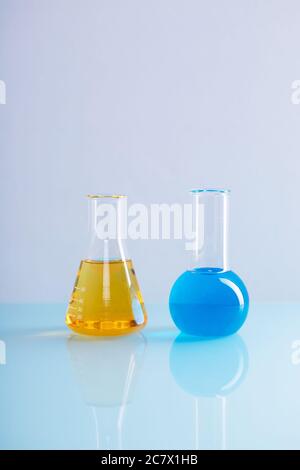 Palloncino verticale di Erlenmeyer con liquido giallo e una matraccio rotondo con liquido blu in laboratorio Foto Stock