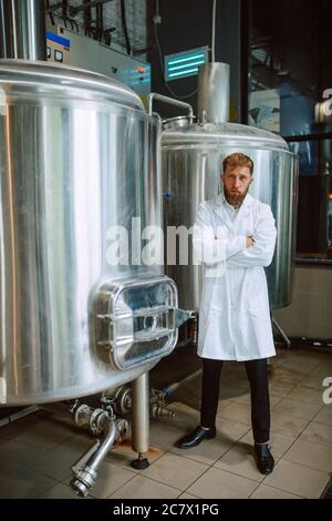 Ritratto di esperto professionale di tecnologo caucasico in uniforme bianca in fabbrica farmaceutica o alimentare - stabilimento di produzione Foto Stock