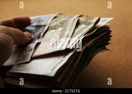 Colpo di closeup di una mano maschio che tiene un pacchetto di Banconote ruble russe Foto Stock