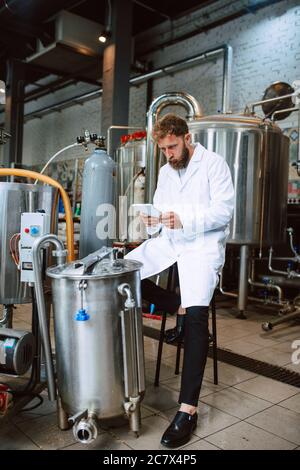 Professionista caucasico bel tecnologo in bianco uniforme standing in fabbrica farmaceutica o alimentare - produzione di controllo impianti Foto Stock