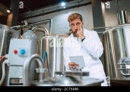 Professionista caucasico bel tecnologo in bianco uniforme standing in fabbrica farmaceutica o alimentare - produzione di controllo impianti Foto Stock