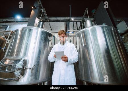 Professionista caucasico bel tecnologo in bianco uniforme standing in fabbrica farmaceutica o alimentare - produzione di controllo impianti Foto Stock