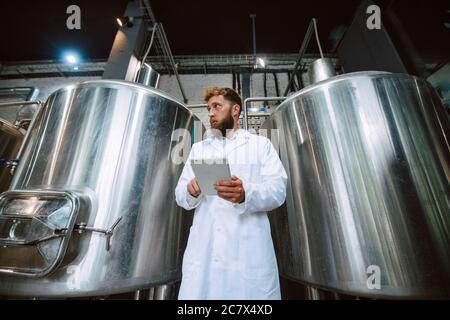 Professionista caucasico bel tecnologo in bianco uniforme standing in fabbrica farmaceutica o alimentare - produzione di controllo impianti Foto Stock