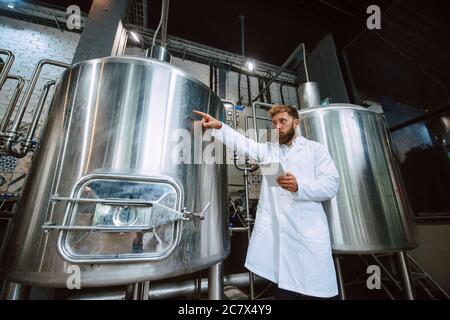 Professionista caucasico bel tecnologo in bianco uniforme standing in fabbrica farmaceutica o alimentare - produzione di controllo impianti Foto Stock