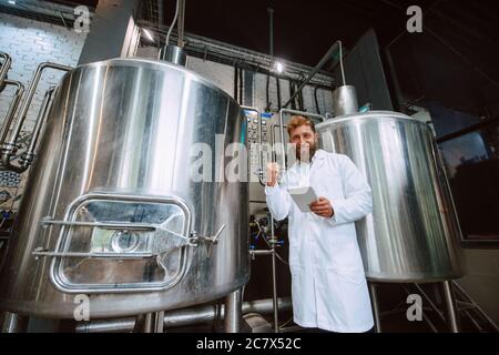 Ritratto di esperto professionale di tecnologo caucasico in uniforme bianca in fabbrica farmaceutica o alimentare - stabilimento di produzione Foto Stock