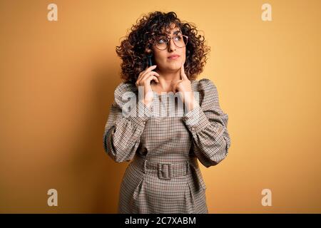 Bella donna d'affari araba indossare occhiali che hanno conversazione parlando su smartphone faccia seria pensare a domanda, idea molto confusa Foto Stock