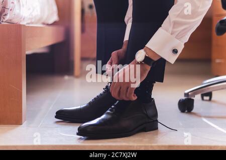 Primo piano di uno sposo che lega le sue scarpe e. preparazione per il matrimonio Foto Stock