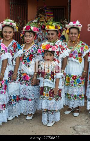 Le donne in hiipil ricamati e cappelli fioriti festive si preparano per la Danza della testa del maiale e del tacchino, o Baile de la cabeza del Foto Stock