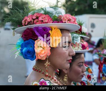 Le donne in hiipil ricamati e cappelli fioriti festive si preparano per la Danza della testa del maiale e del tacchino, o Baile de la cabeza del Foto Stock