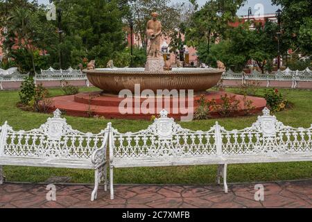 Panchine del parco in ghisa e una fontana con una statua di una donna Maya nel parco Francisco Cantón Rosado. Valladolid, Yucatan, Messico. Foto Stock