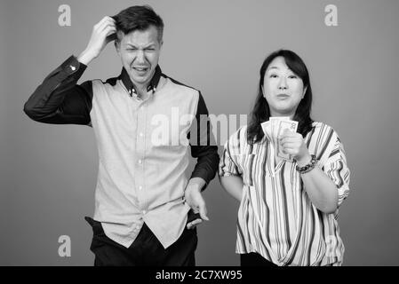 Giovane bell'uomo d'affari e matura donna d'affari asiatica su sfondo grigio Foto Stock