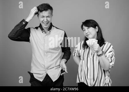Giovane bell'uomo d'affari e matura donna d'affari asiatica su sfondo grigio Foto Stock