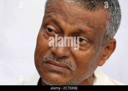 Triste o pensoso uomo indiano volto ritratto su sfondo bianco. Vecchio uomo guardando lato. Foto Stock