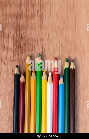 Immagine verticale di matite colorate di colori diversi su un superficie in legno Foto Stock