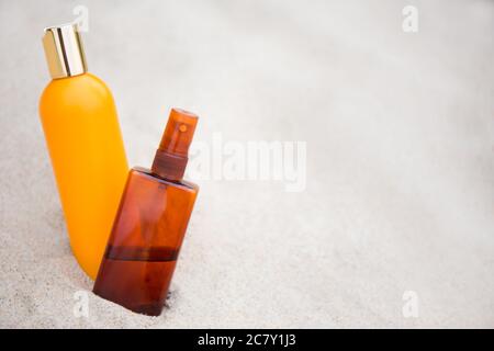 concetto di cura della pelle - primo piano di bottiglie di crema solare nella sabbia Foto Stock