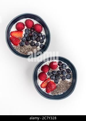 Due ciotole blu con yogurt e frutta isolati su sfondo bianco. Foto Stock