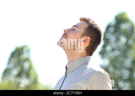 Vista laterale di un uomo che respira aria fresca in piedi all'aperto su un parco verde Foto Stock